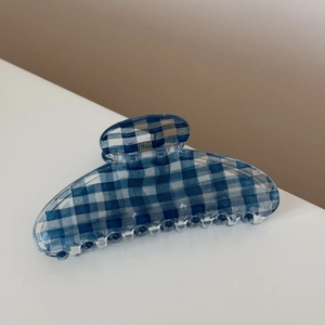 Detailed view of the blue gingham pattern and glossy texture on a hair claw clip
