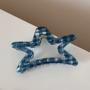 Detail shot of a star-shaped hair claw clip with a blue and white gingham pattern