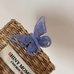 Detail of the marbled purple and blue acetate butterfly hair clip on a woven basket