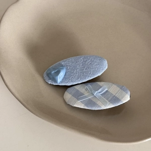 Detailed view of blue and white checkered hair clips with bow and heart accents