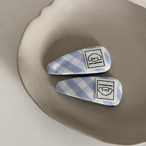 Detail of blue and white plaid hair clips with cute puppy patch in a ceramic tray
