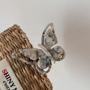 Detailed macro view of the acetate butterfly clip with elegant marble grey textures