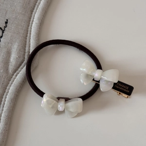 Détail de la barrette à nœud en acétate blanc et de l'élastique à effet perlé