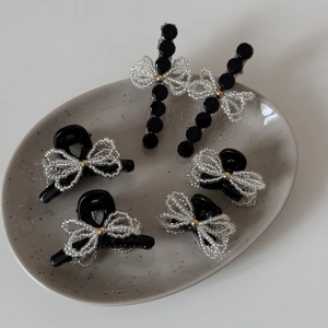 Detailed set of black butterfly hair clips with transparent beads on a ceramic tray