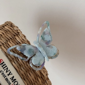 Macro detail of a colorful marble butterfly clip with SAN engraving on woven fabric