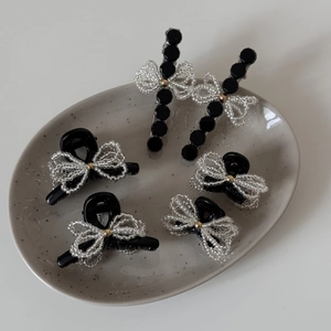 Elegant 6-piece beaded bow hair clip set with black acrylic and white pearls in a ceramic tray