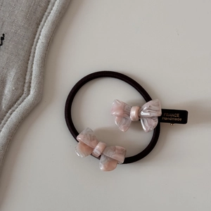 Détail d'un ensemble de chouchous et barrettes à nœuds en acétate marbré rose