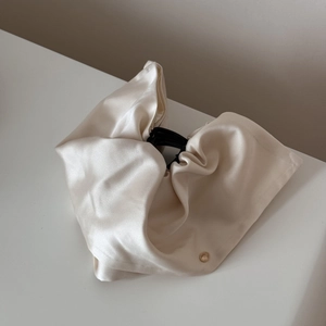 Detail of elegant beige satin hair claw clip with a luxury golden metal button accent