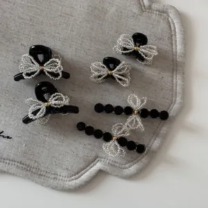 Detail shot of mini black hair clips and beaded bow hairpins on a linen tray