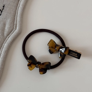 Détail d'un ensemble barrette et élastique en acétate écaille de tortue avec texte doré