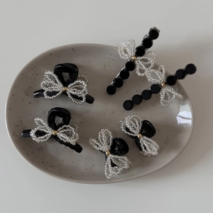 Detail of five-piece hair clip set with white bead bows on black resin finish