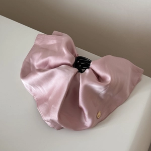Close-up of pink satin hair claw clip with silk texture and gold metal detail