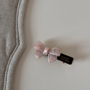Détail de la barrette à nœud en acétate rose marbré avec logo doré France Handmade