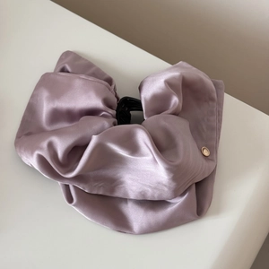 Detail of lavender satin hair claw clip with pleated texture and gold metal button