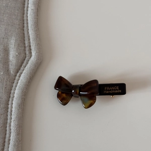 Gros plan d'une barrette nœud en écaille avec inscription dorée France Handmade