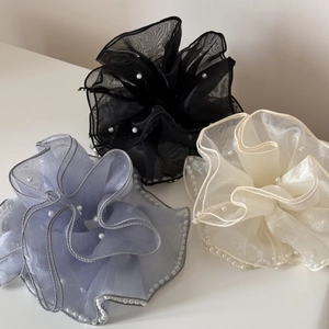 Détails de chouchous géants en organza noir, bleu et beige ornés de perles nacrées