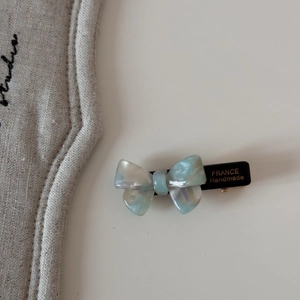 Vue détaillée d'une barrette nœud en acétate avec texture marbrée et lettres dorées