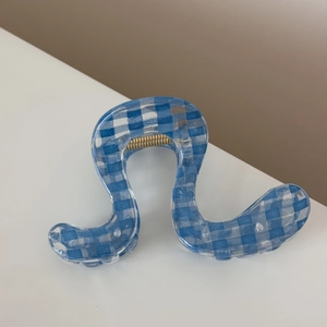 Close-up of blue checkered hair claw clip with wave design and golden metal spring
