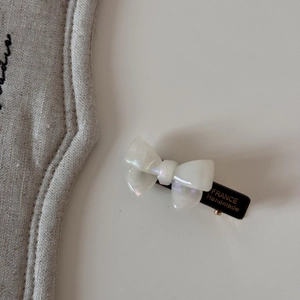Détail d'une barrette à nœud blanc nacré avec l'inscription dorée France Handmade