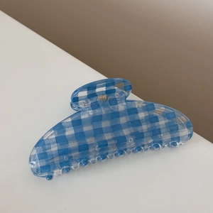 Detail view of a light blue plaid hair claw clip with a glossy translucent resin finish