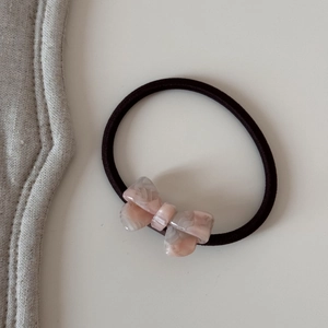 Macro d'un chouchou avec nœud en acétate rose marbré et élastique noir haute résistance