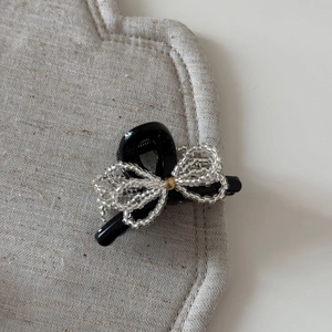 Close-up of black hair claw clip featuring a handcrafted clear beaded bow with golden bead