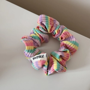 Gros plan d'un chouchou en tricot rayé arc-en-ciel avec texture et étiquette de marque