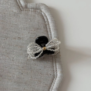 Close-up of elegant black hair claw clip with transparent beaded bow and golden bead detail