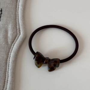 Détail d'un élastique à cheveux noir avec un nœud en acétate écaille de tortue