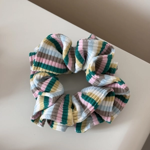 Détail d'un chouchou en tricot rayé coloré montrant le tissu côtelé doux et la texture vive