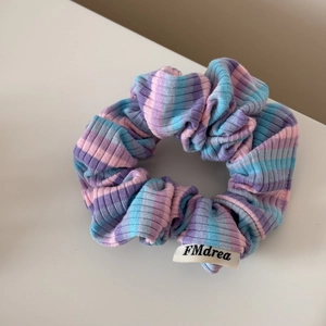 Détail rapproché du chouchou en maille rayée colorée avec étiquette de marque FMdrea