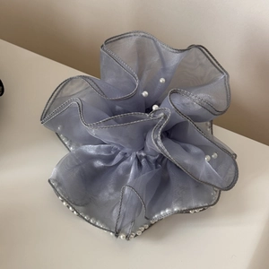 Détail d'un chouchou géant en organza gris orné de perles blanches et de volants