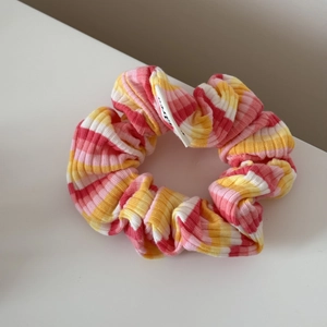 Détail du chouchou en maille côtelée avec des rayures estivales jaunes et roses vives