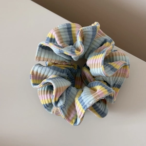 Vue détaillée d'un chouchou en tricot rayé coloré aux textures rose jaune et verte