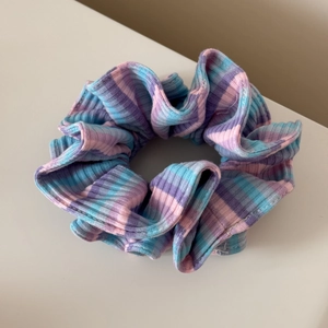 Gros plan d'un chouchou en tricot côtelé avec des rayures dégradées roses, mauves et bleues