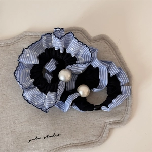 Chouchou à rayures bleues avec grande perle blanche sur un support en lin doux