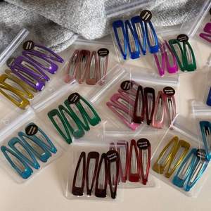 Set of 4 colorful translucent triangular and teardrop hair clips in transparent packaging