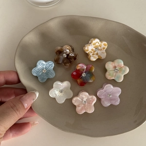 Détail de mini pinces à cheveux fleur en acétate avec strass brillants de diverses couleurs