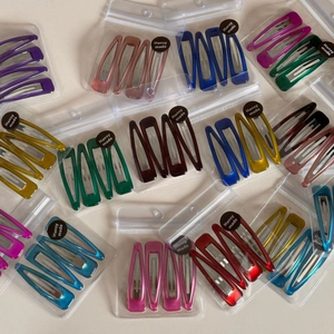 Detailed view of colorful glossy metal drop hair clips in transparent gift packaging