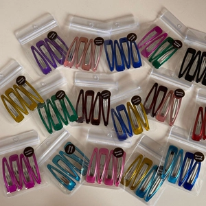 Detailed view of colorful metal snap hair clips in branded clear packaging bags
