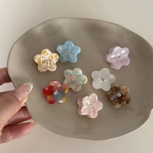 Huit mini barrettes à fleurs en acétate avec strass présentées dans un plateau en céramique