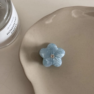 Détail de la pince à cheveux fleur bleue avec un centre en strass brillant et élégant