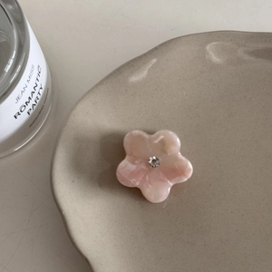 Vue détaillée d'une pince à cheveux florale en acétate rose avec un strass central étincelant
