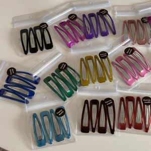 Close-up of colorful metal water drop hair clips set in transparent zip bags