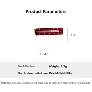 Detail view of a red polka dot hair clip with dimensions 7cm by 1.7cm on white backdrop