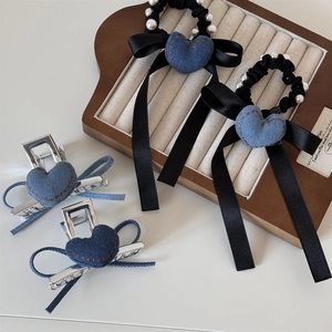 Dettaglio di elastici a cuore in denim con nastri neri e clip metalliche con perle
