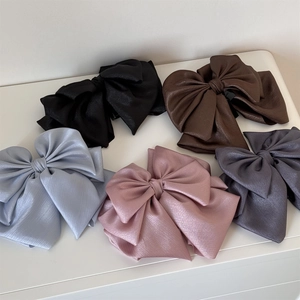 Detailed view of large multi-layer satin bow hair claws in five different elegant colors