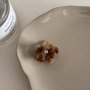 Détail d'une mini pince à cheveux en acétate fleurie avec motif écaille et petit strass