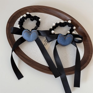 Dettaglio dell'elastico cuore in denim con perle e lunghi nastri di raso neri