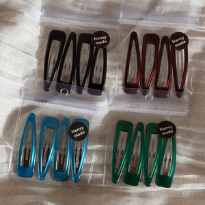 Set of 4 geometric water drop hair clips in diverse glossy colors with retail packaging